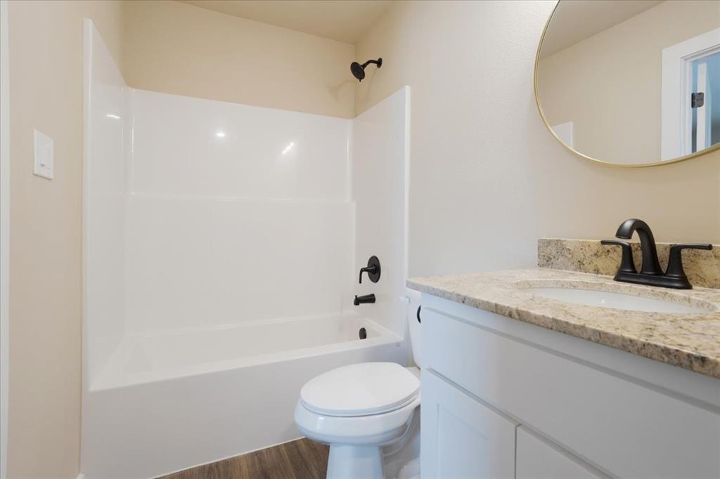 2385 Miller Street Denison, TX 75020 - Photo 16 of 26 a bathroom with a granite countertop sink a toilet and a mirror