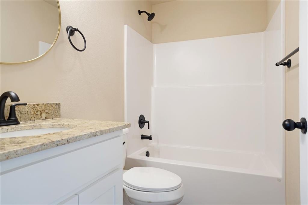 2385 Miller Street Denison, TX 75020 - Photo 21 of 26 a bathroom with a granite countertop bathtub shower sink vanity and toilet
