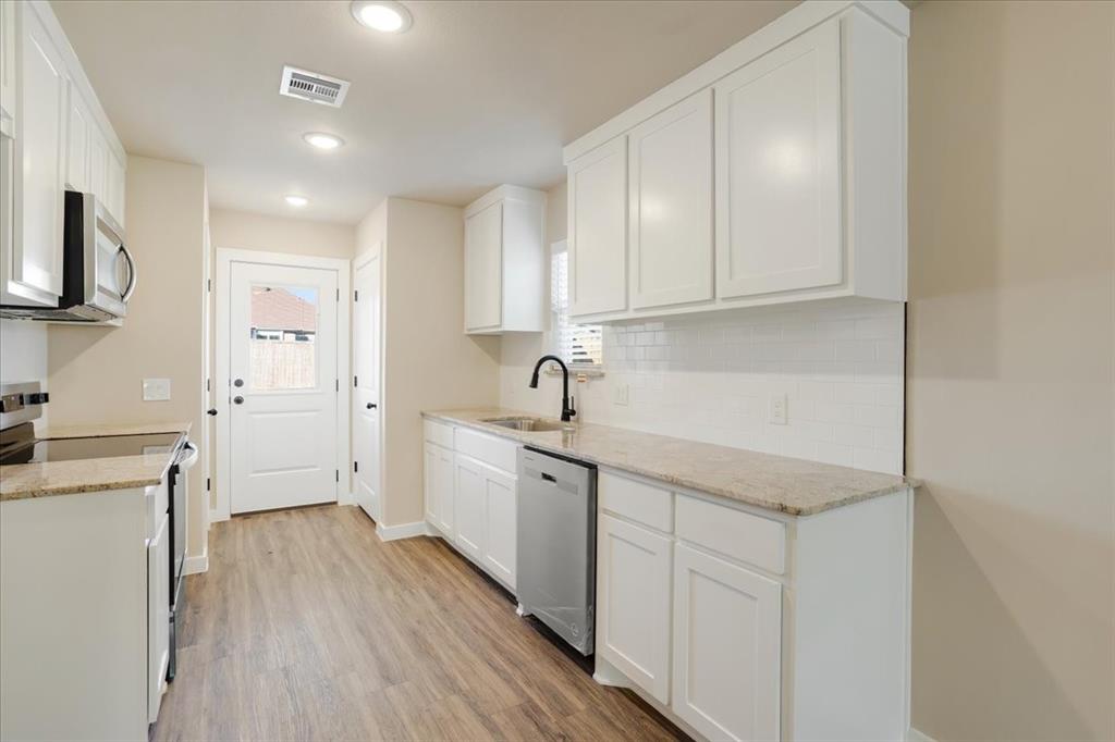 2385 Miller Street Denison, TX 75020 - Photo 9 of 26 a kitchen with sink cabinets and wooden floor