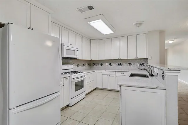 a kitchen with white cabinets and appliances
