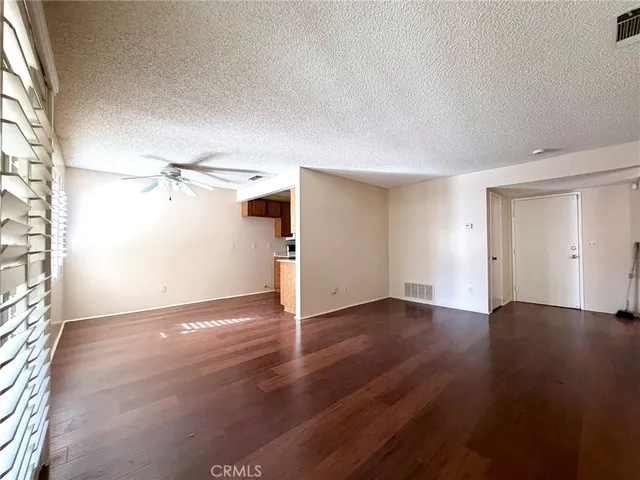 an empty room with wooden floor ceiling fan and windows