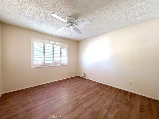 an empty room with wooden floor fan and windows