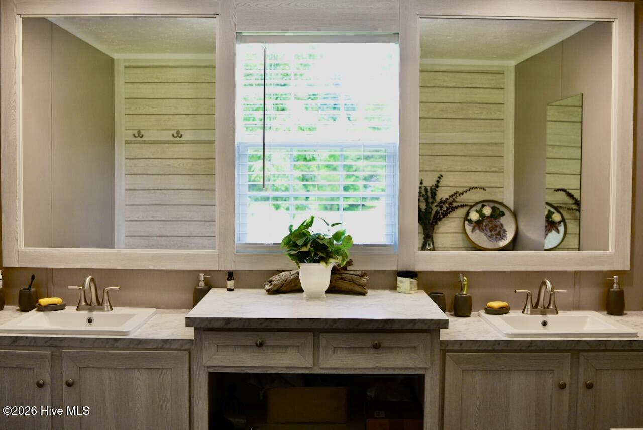 1430 Nixonton Road Elizabeth City, NC 27909 - Photo 21 of 30 The primary suite offers a large vanity area with 2 tall sinks, 2 individual mirrors and a full length mirror on the wall to the right. There is storage space below the sinks and vanity.