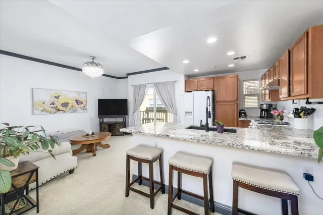 a kitchen with stainless steel appliances granite countertop dining table chairs refrigerator and sink