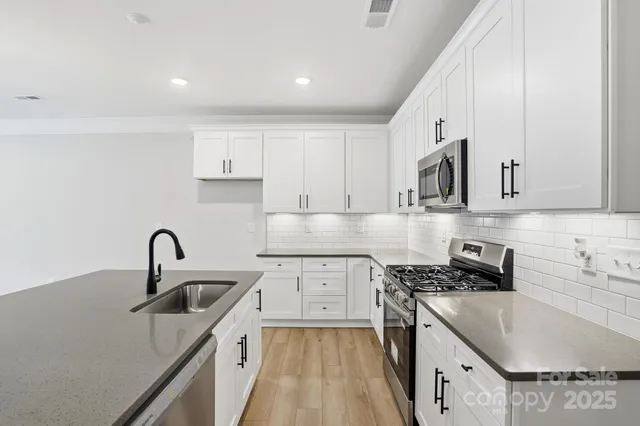 a kitchen with stainless steel appliances granite countertop a sink stove and refrigerator