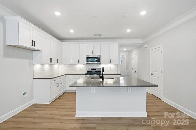 a kitchen with granite countertop white cabinets stainless steel appliances and sink