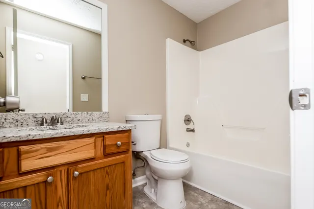 a bathroom with a granite countertop sink a toilet and a bathtub