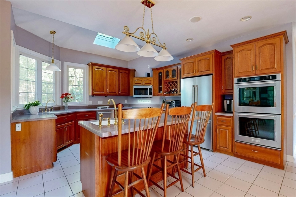 7 Riverbend Road Upton, MA 01568 - Photo 10 of 39 a kitchen with stainless steel appliances granite countertop a stove top oven a sink dishwasher a dining table and chairs with wooden floor