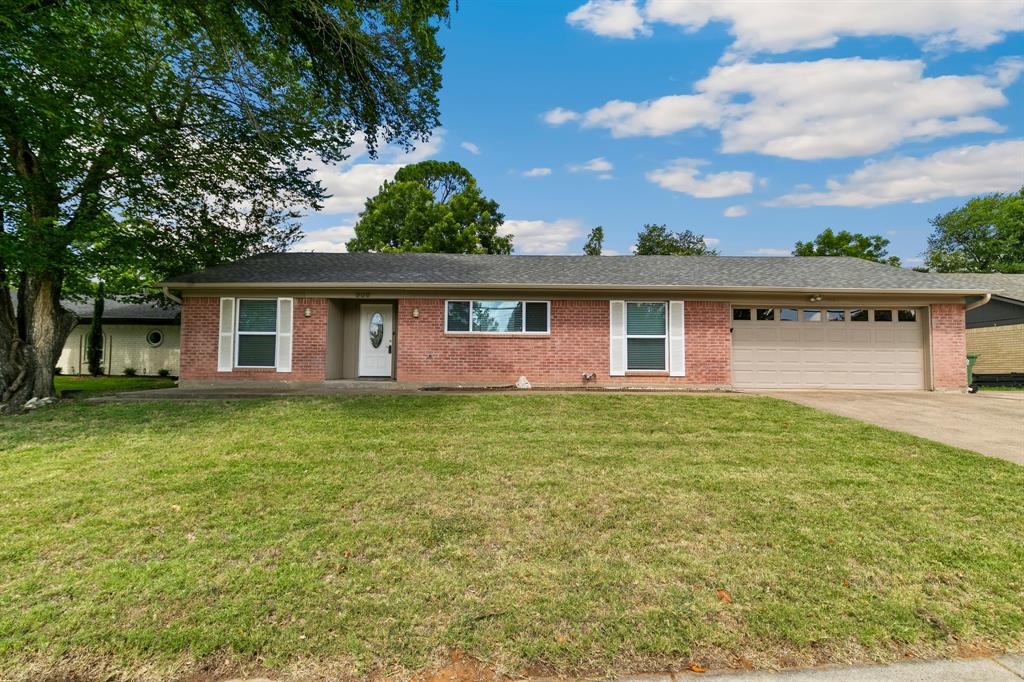 909 North Dove Road Grapevine, TX 76051 - Photo 1 of 30 Brick exterior home featuring a well-maintained lawn, a two-car garage with panel windows, a covered front entry, and mature trees framing the property