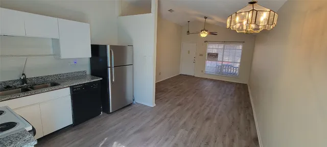 a kitchen with granite countertop a refrigerator and a stove top oven