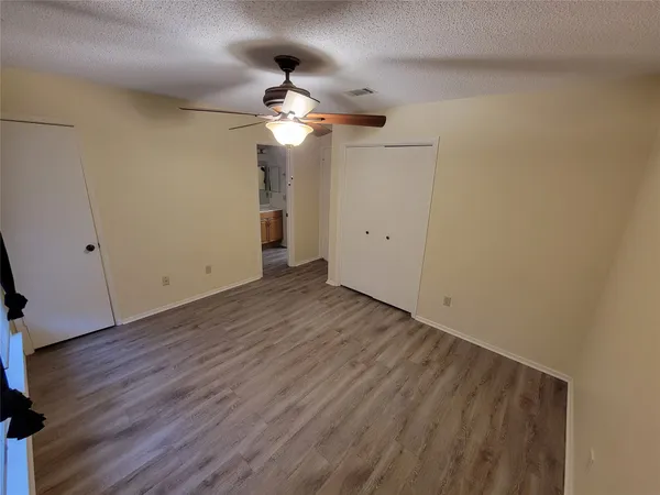 an empty room with wooden floor a ceiling fan and windows