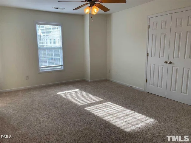 a view of an empty room with window and chandelier fan