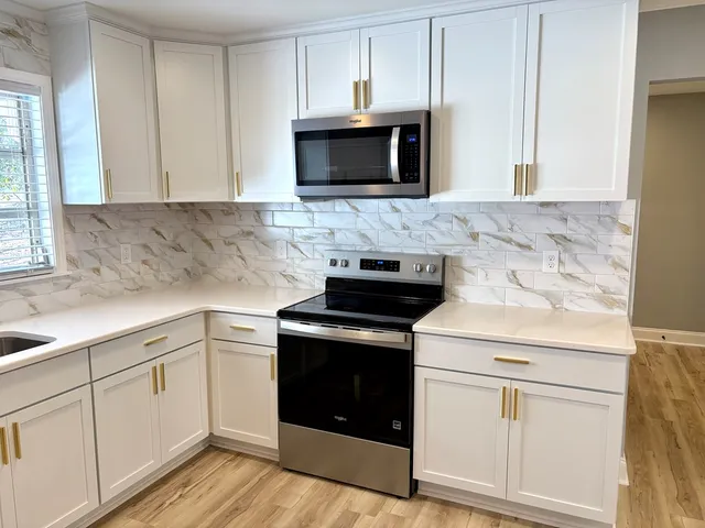 a kitchen with granite countertop white cabinets and white appliances