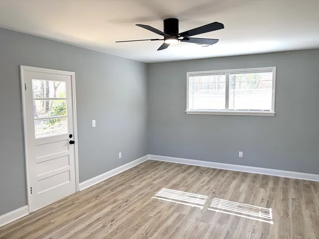 an empty room with windows and ceiling fan