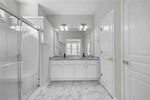 a bathroom with a granite countertop sink a mirror a vanity and a shower