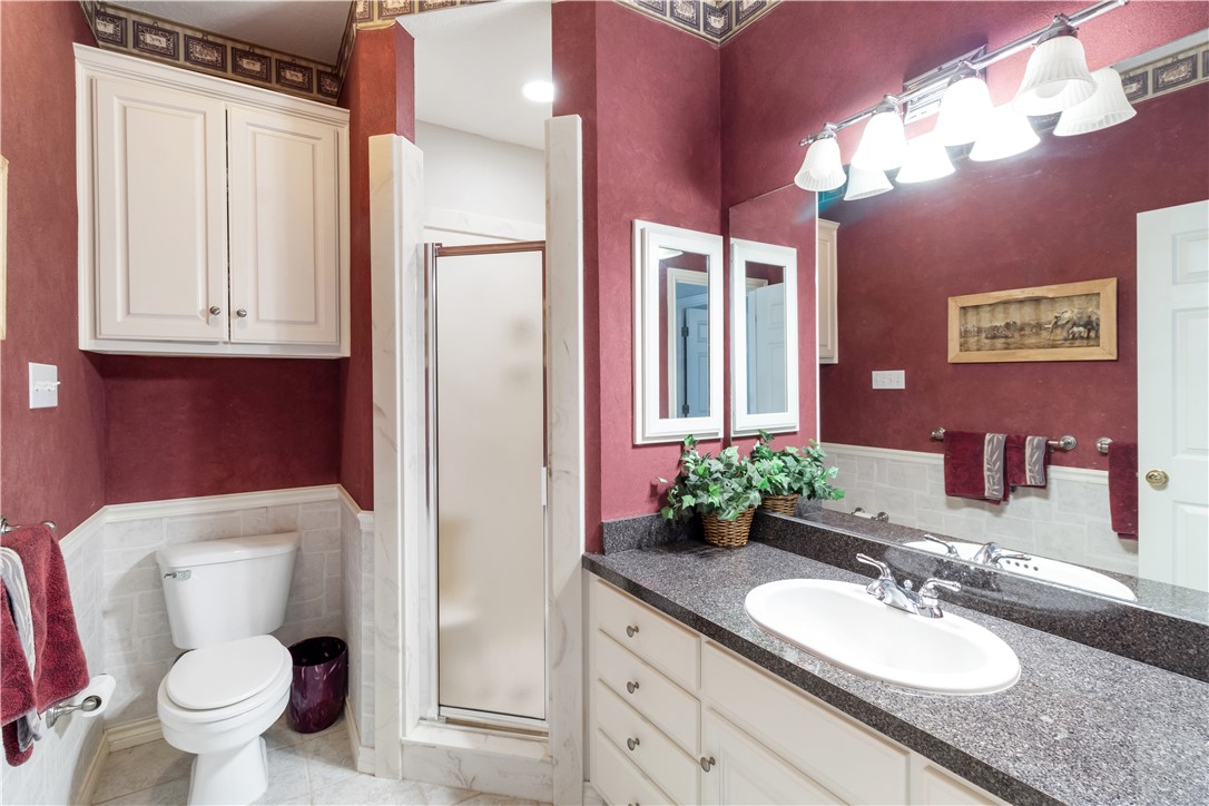 28109 Waller Gladish Road Waller, TX 77484 - Photo 20 of 28 a bathroom with a granite countertop toilet sink and mirror