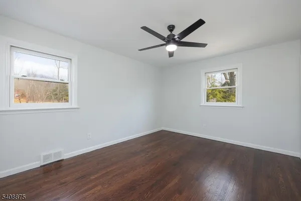 a view of a big room with wooden floor and windows