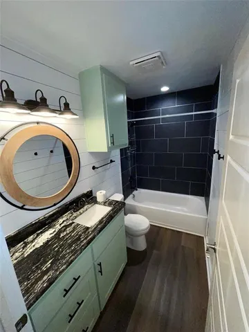 a bathroom with a granite countertop toilet sink and mirror