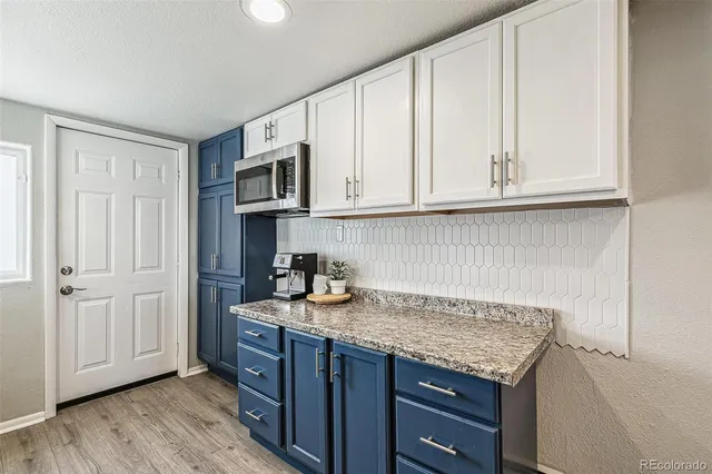 a kitchen with granite countertop a sink cabinets and a wooden floor