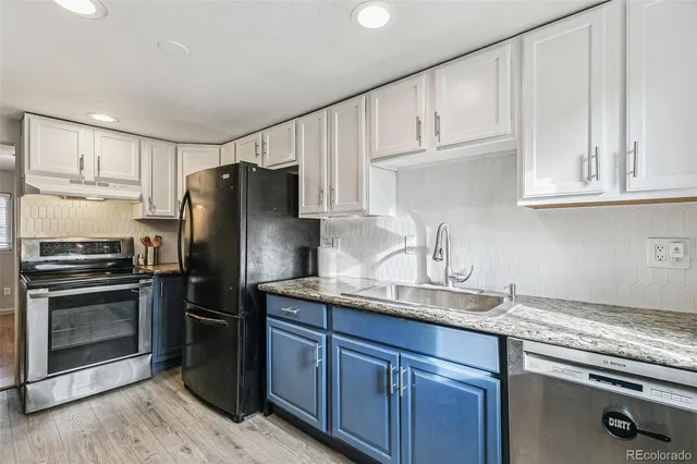 a kitchen with granite countertop a refrigerator sink and cabinets