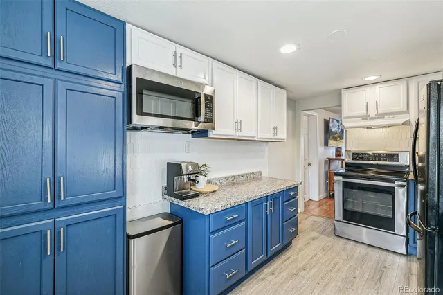 a kitchen with granite countertop wooden cabinets stainless steel appliances and a wooden floor