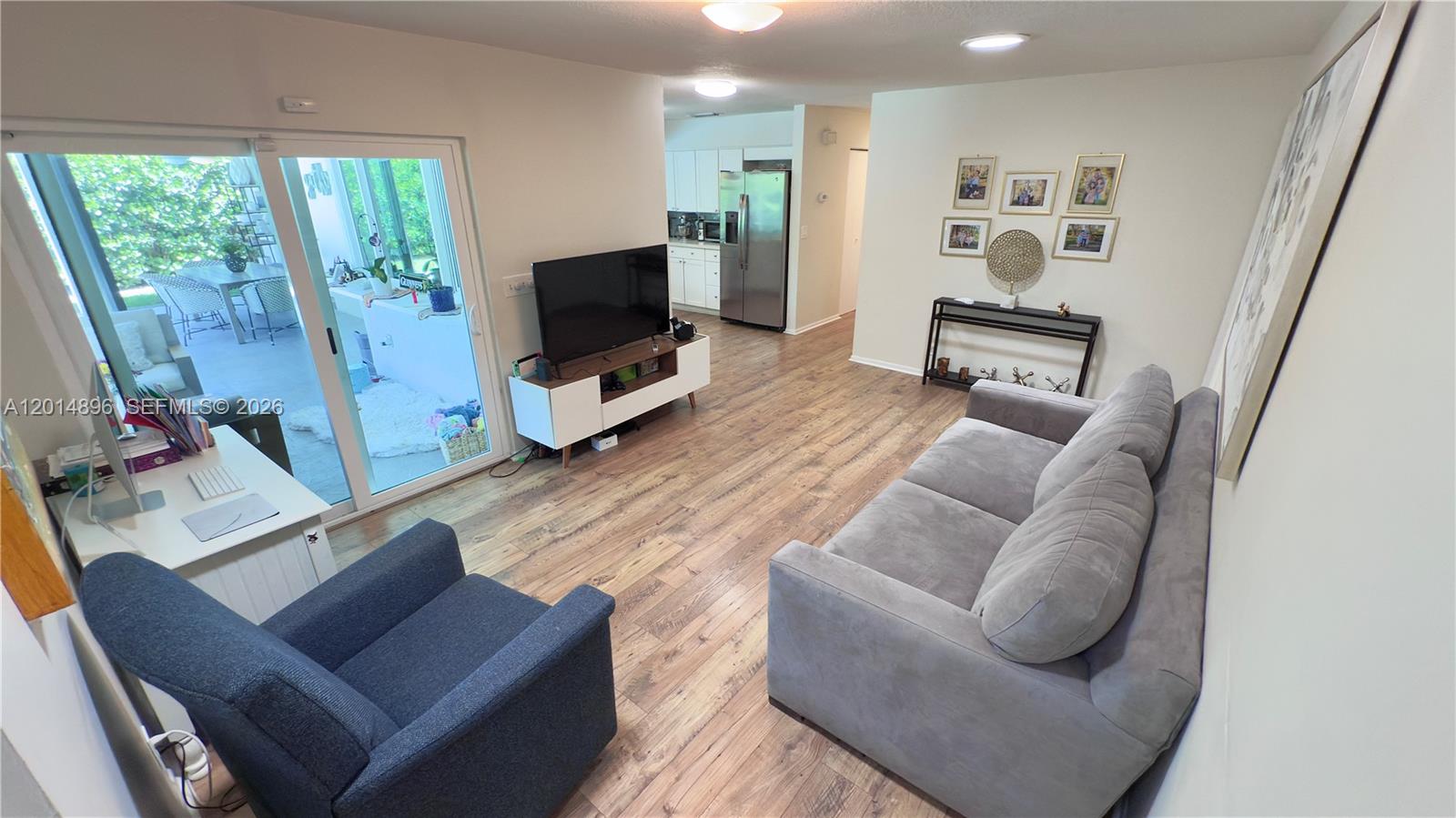 2411 Northwest 31st Street Boca Raton, FL 33431 - Photo 11 of 43 a living room with furniture a flat screen tv and a floor to ceiling window