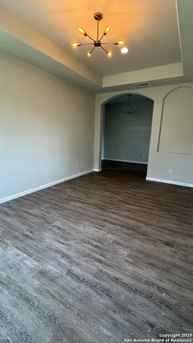 a view of an empty room with wooden floor and ceiling fan