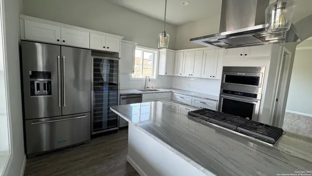 a kitchen with kitchen island a counter top a refrigerator a sink and a stove