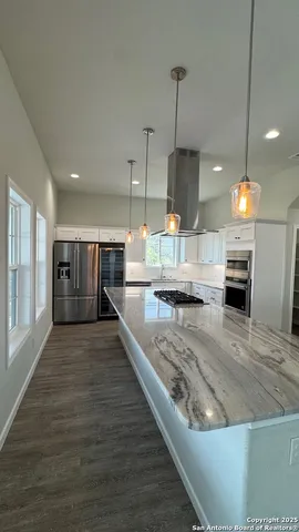 a view of a kitchen with kitchen island a counter top space a sink and appliances