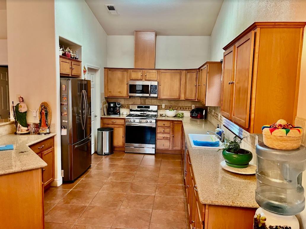 922 Sequoia Street Parlier, CA 93648 - Photo 4 of 16 a kitchen with stainless steel appliances granite countertop a sink a stove and a refrigerator