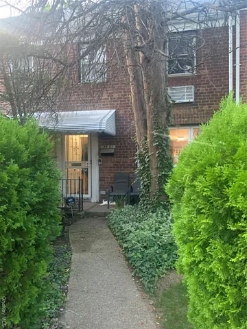 a view of a brick house with a yard and plants