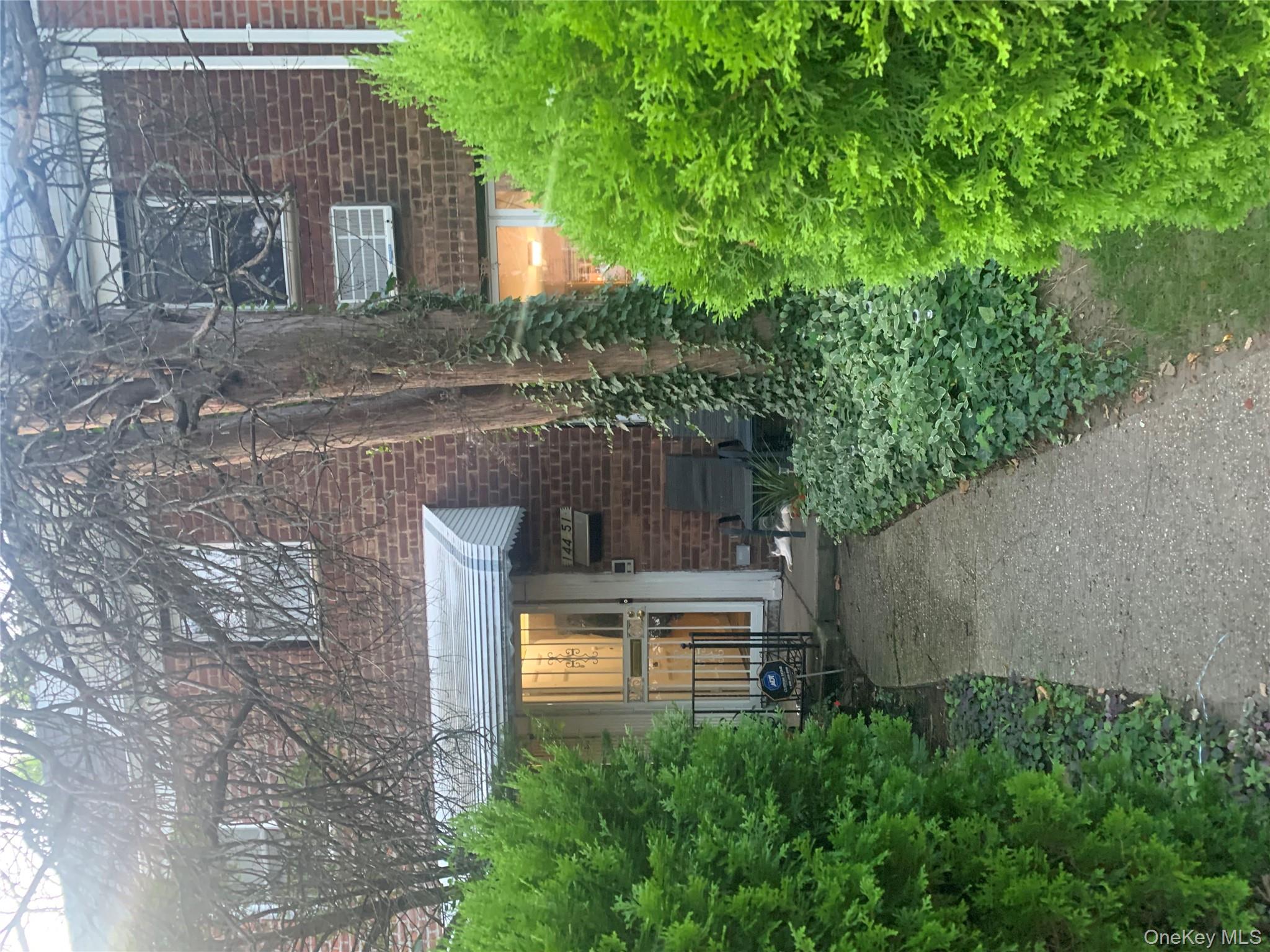 a view of a brick house with a yard and plants
