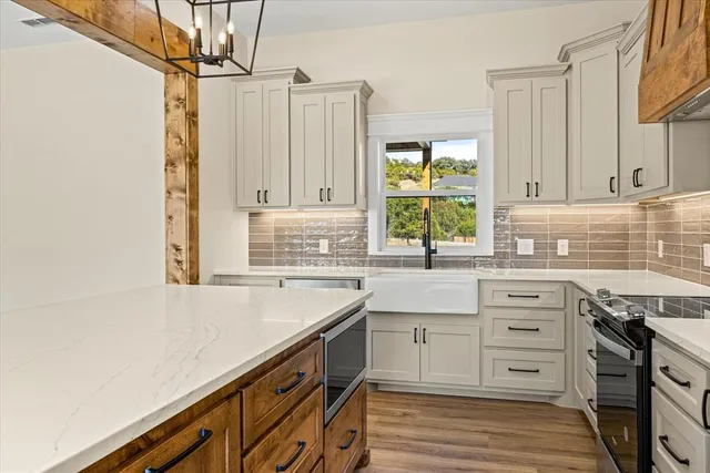 a kitchen with granite countertop a sink cabinets stainless steel appliances and a window