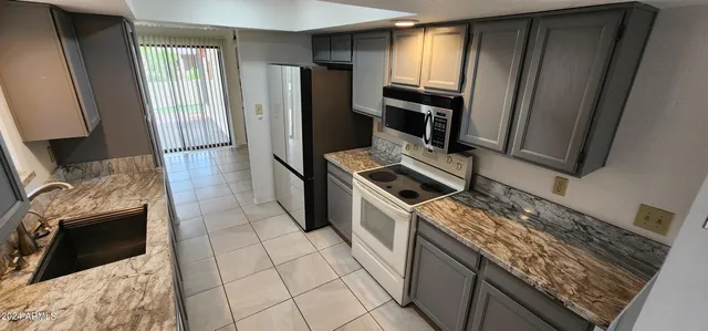 a kitchen with granite countertop a sink stove and refrigerator