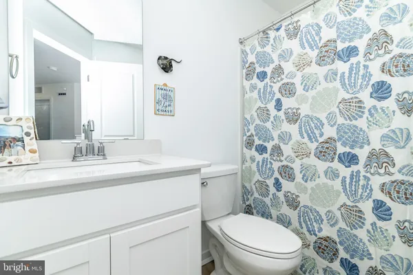 a bathroom with a granite countertop toilet a sink a mirror and a shower curtain