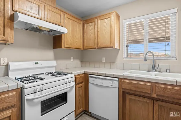 a kitchen with granite countertop a sink cabinets stainless steel appliances and a window