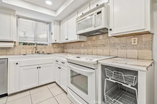 a kitchen with white cabinets and white appliances