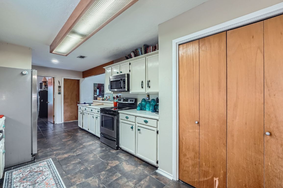 760 Skyline Ridge Lookout Wimberley, TX 78676 - Photo 13 of 40 Kitchen featuring appliances with stainless steel finishes, light countertops, stone finish flooring, and white cabinets