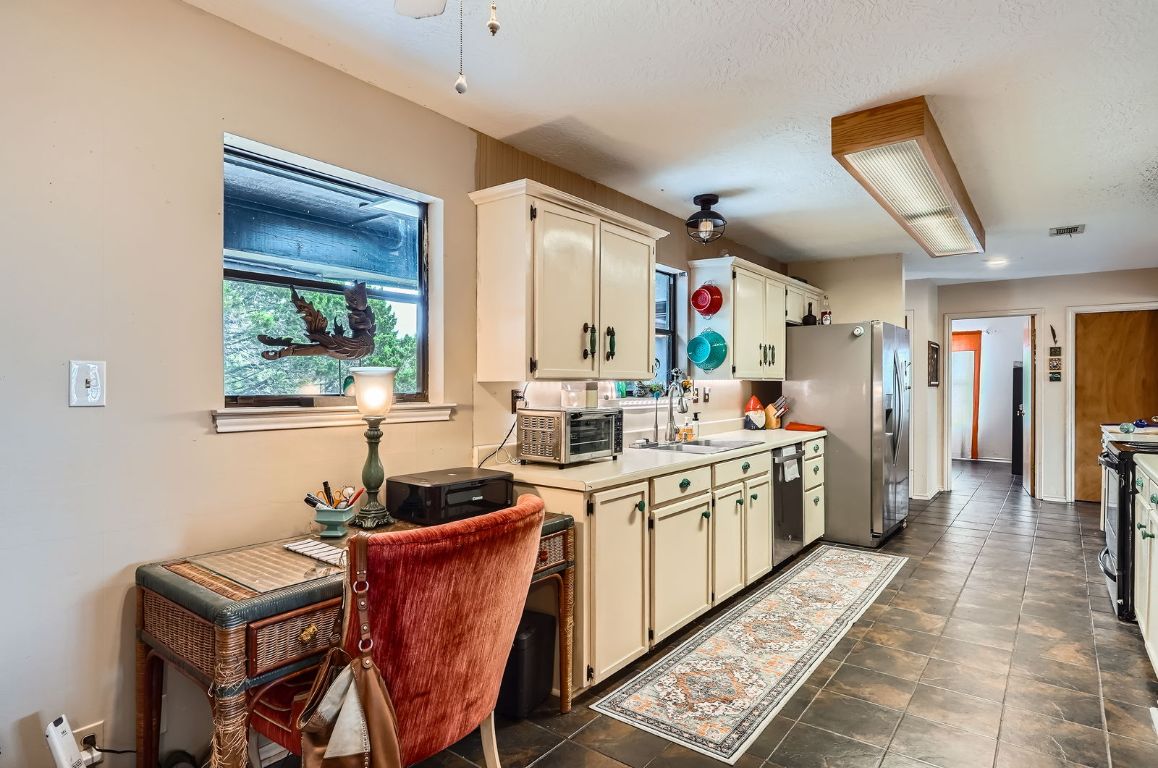 760 Skyline Ridge Lookout Wimberley, TX 78676 - Photo 15 of 40 Kitchen featuring stainless steel appliances, light countertops, and cream cabinetry
