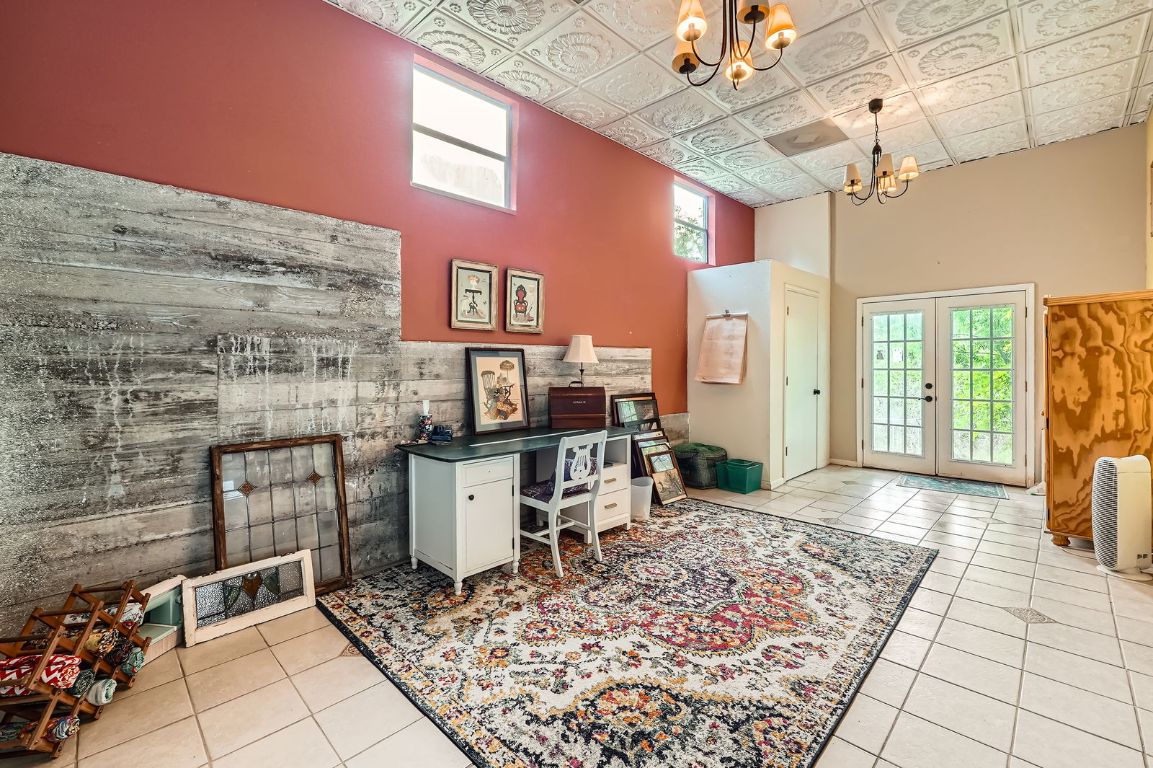 760 Skyline Ridge Lookout Wimberley, TX 78676 - Photo 16 of 40 Home office with a chandelier, a high ceiling, french doors, healthy amount of natural light, and light tile patterned flooring