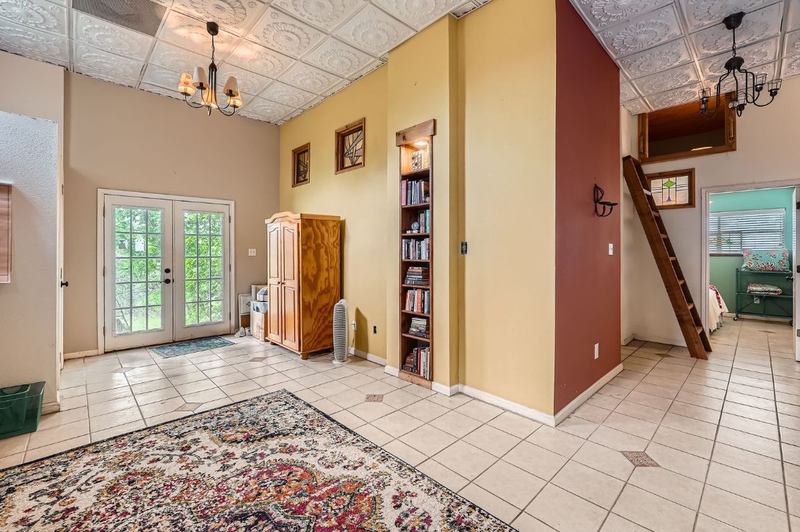 760 Skyline Ridge Lookout Wimberley, TX 78676 - Photo 17 of 40 Entrance foyer with an ornate ceiling, a chandelier, light tile patterned flooring, french doors, and a high ceiling