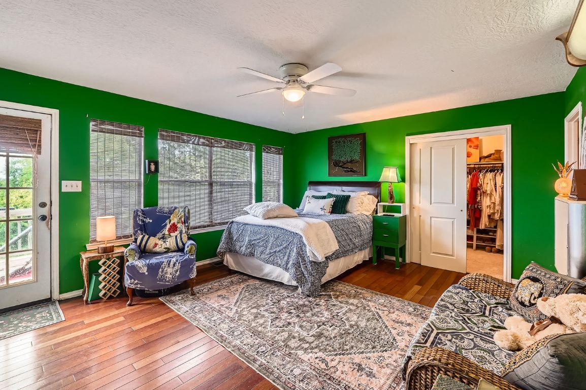 760 Skyline Ridge Lookout Wimberley, TX 78676 - Photo 19 of 40 Bedroom featuring hardwood / wood-style flooring, access to outside, ceiling fan, and a textured ceiling
