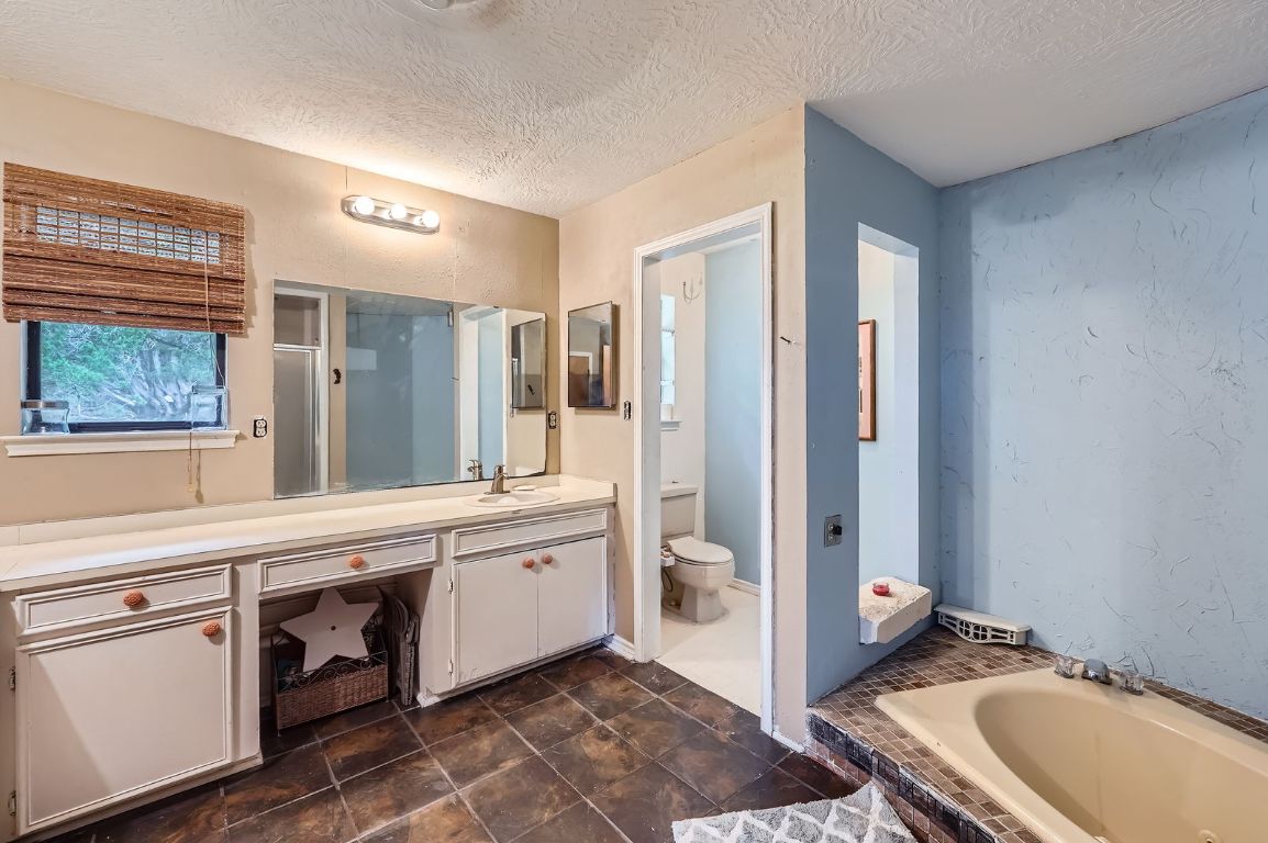 760 Skyline Ridge Lookout Wimberley, TX 78676 - Photo 22 of 40 Full bath featuring vanity, a tub with jets, a textured ceiling, and an enclosed shower
