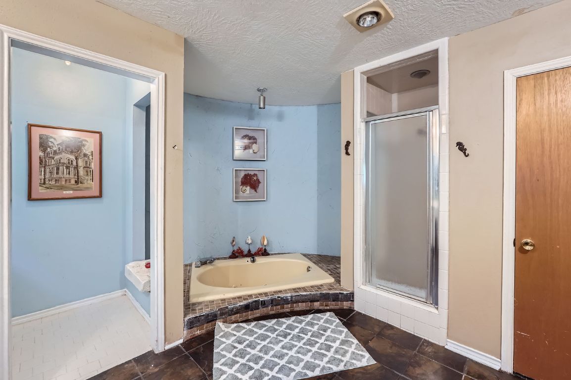 760 Skyline Ridge Lookout Wimberley, TX 78676 - Photo 23 of 40 Full bath featuring a bath, a stall shower, a textured ceiling, and tile patterned flooring