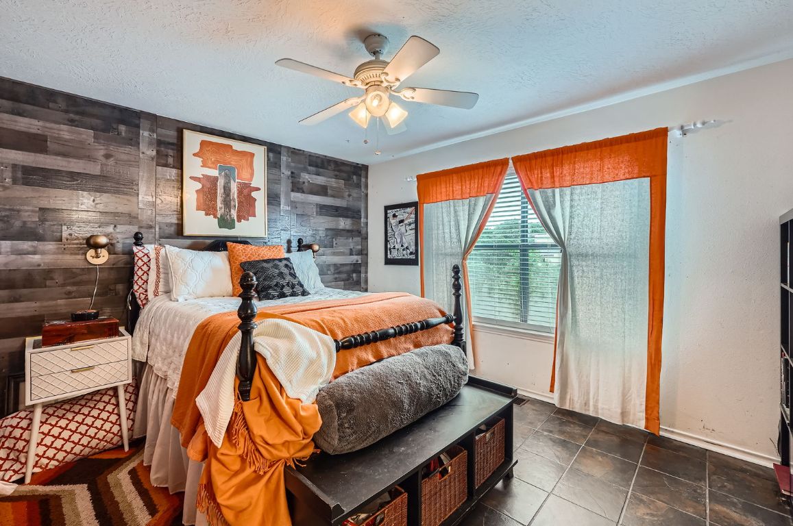 760 Skyline Ridge Lookout Wimberley, TX 78676 - Photo 25 of 40 Bedroom with wood walls, a textured ceiling, and ceiling fan