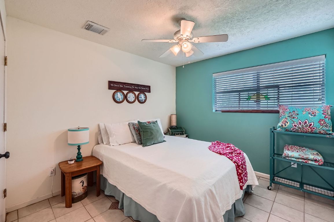 760 Skyline Ridge Lookout Wimberley, TX 78676 - Photo 29 of 40 Bedroom with tile patterned flooring, ceiling fan, and a textured ceiling