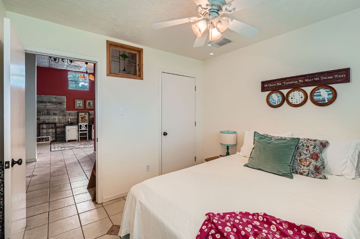 760 Skyline Ridge Lookout Wimberley, TX 78676 - Photo 30 of 40 Bedroom featuring light tile patterned flooring, a ceiling fan, and a textured ceiling