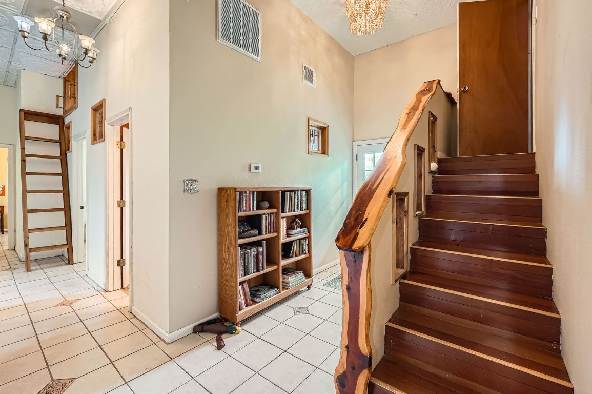 760 Skyline Ridge Lookout Wimberley, TX 78676 - Photo 31 of 40 Stairs featuring a chandelier, tile patterned flooring, and a towering ceiling