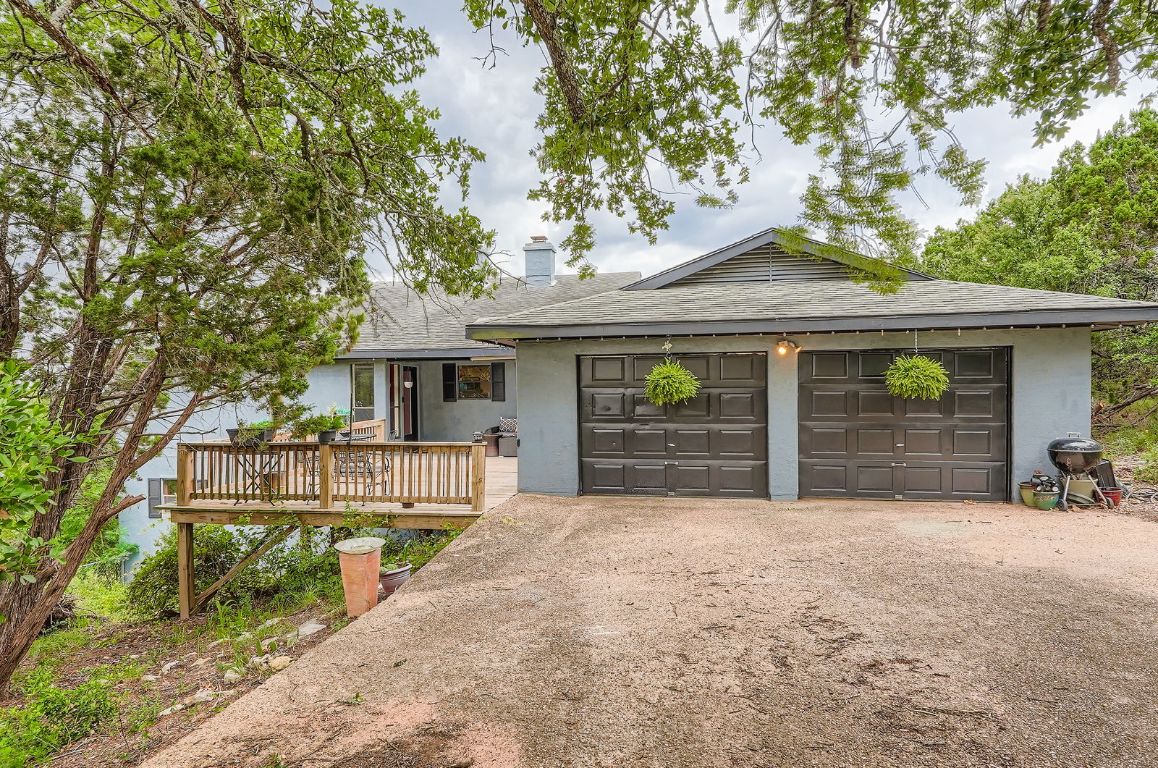 760 Skyline Ridge Lookout Wimberley, TX 78676 - Photo 33 of 40 Ranch-style home featuring a shingled roof, a chimney, driveway, a wooden deck, and an attached garage