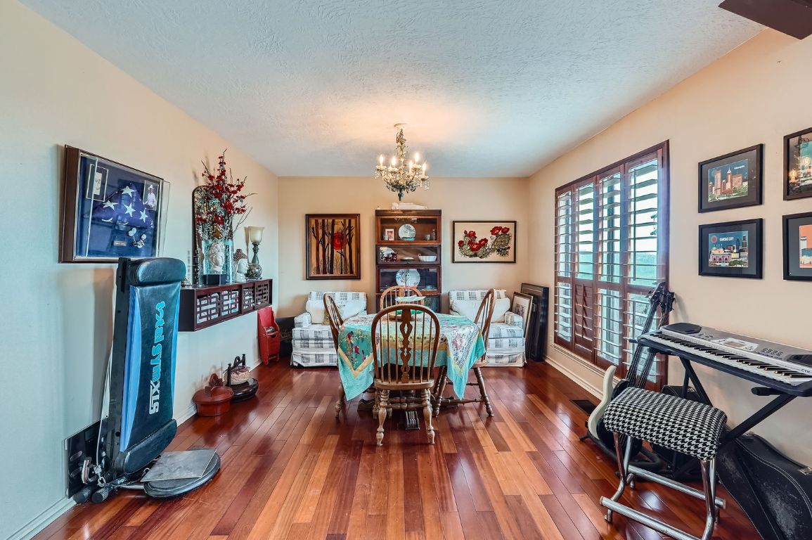 760 Skyline Ridge Lookout Wimberley, TX 78676 - Photo 10 of 40 Dining room featuring a chandelier, hardwood / wood-style floors, and a textured ceiling